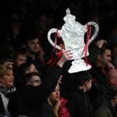 A fan holds up a homemade FA Cup trophy. The first round proper of the competition gets underway this weekend, with plenty of potential for upsets
