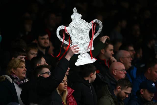 A fan holds up a homemade FA Cup trophy. The first round proper of the competition gets underway this weekend, with plenty of potential for upsets