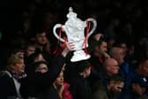 A fan holds up a homemade FA Cup trophy. The first round proper of the competition gets underway this weekend, with plenty of potential for upsets