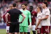 David Raya debates with referee Chris Kavanagh as they wait for VAR's decision.